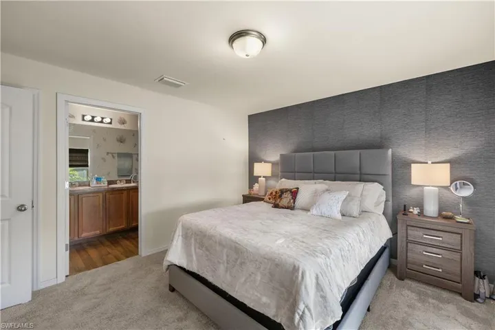 Bedroom featuring connected bathroom, sink, and light colored carpet