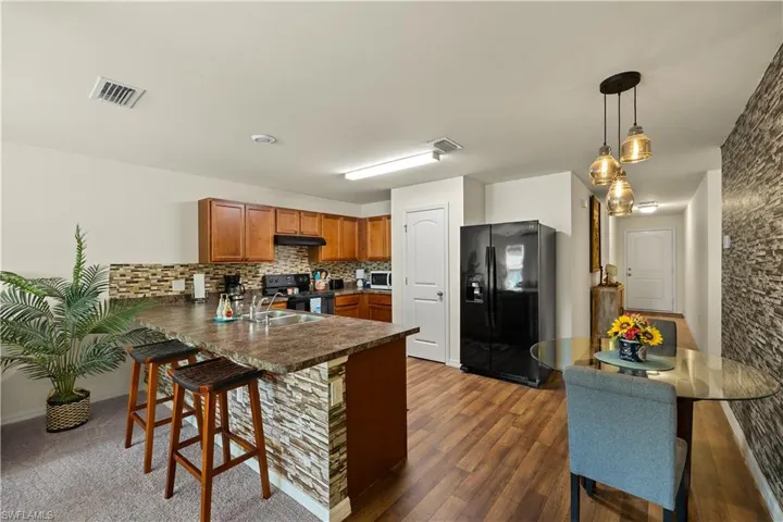 Kitchen with kitchen peninsula, decorative light fixtures, black appliances, sink, and backsplash