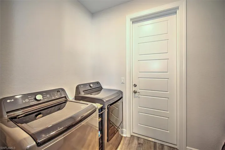 Washroom with washer and dryer and hardwood / wood-style flooring