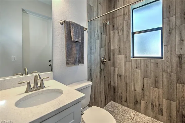 Bathroom with tiled shower, vanity, and toilet