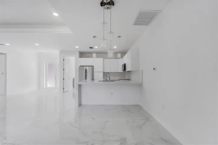 Kitchen featuring white cabinetry, sink, pendant lighting, and appliances with stainless steel finishes