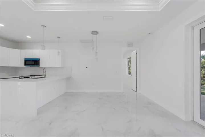 Kitchen featuring white cabinets, plenty of natural light, crown molding, and hanging light fixtures