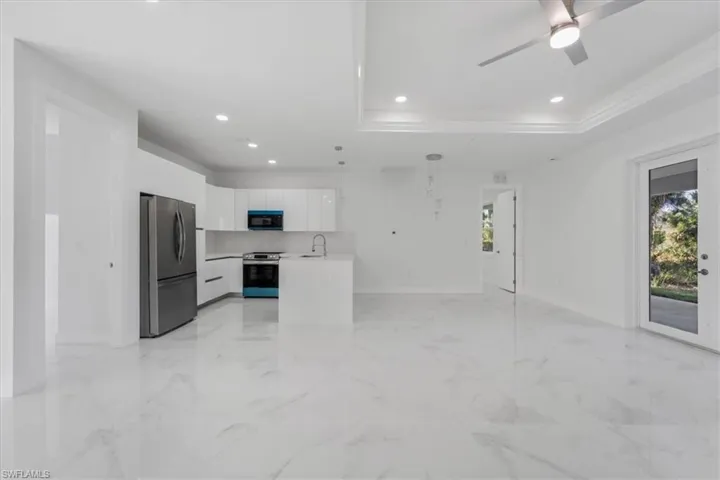 Kitchen featuring pendant lighting, a raised ceiling, sink, appliances with stainless steel finishes, and white cabinetry