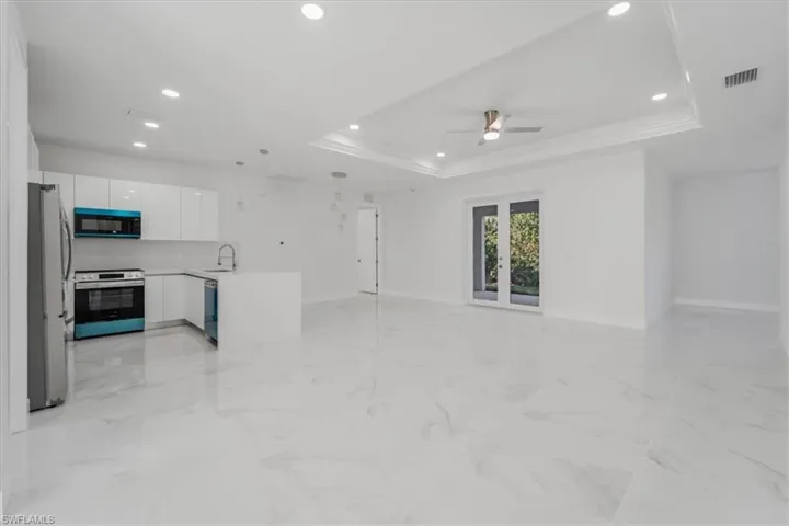 Living room with a tray ceiling, ceiling fan, ornamental molding, and sink