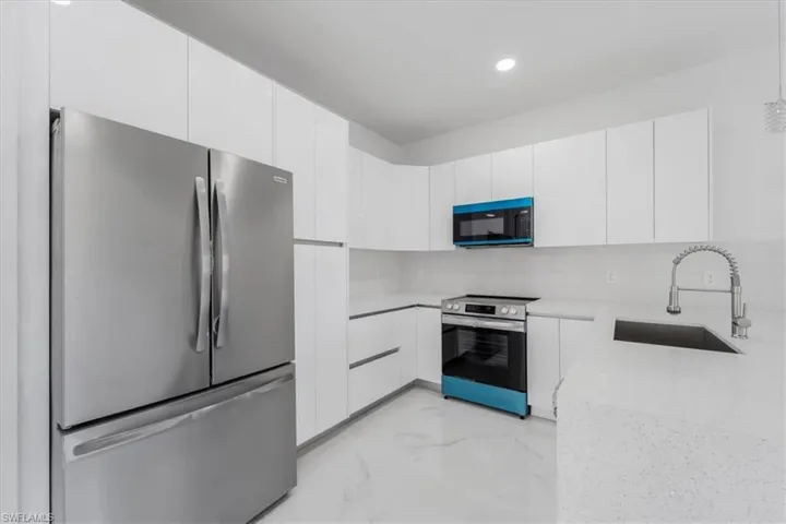 Kitchen featuring stainless steel appliances, white cabinetry, and sink