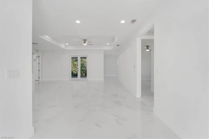 Empty room featuring ceiling fan, ornamental molding, and a tray ceiling