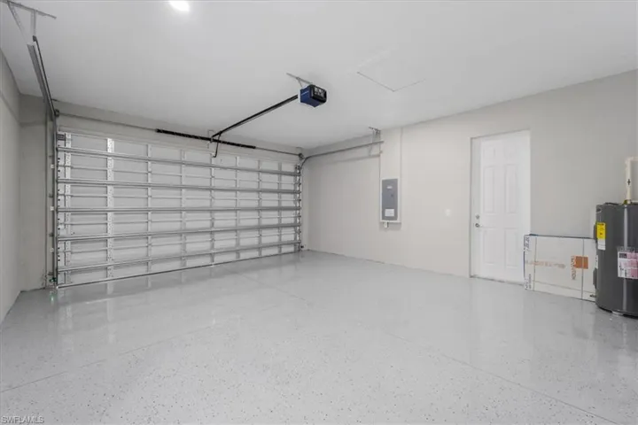 Garage with electric panel, electric water heater, and a garage door opener