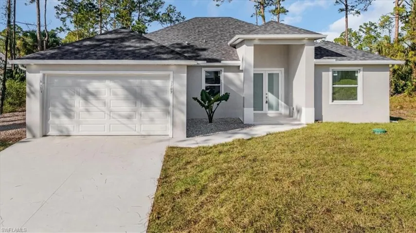 View of front of property with french doors, a garage, and a front lawn