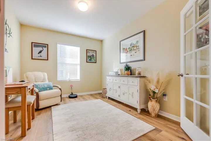 Den featuring light laminate flooring and french glass-grid doors