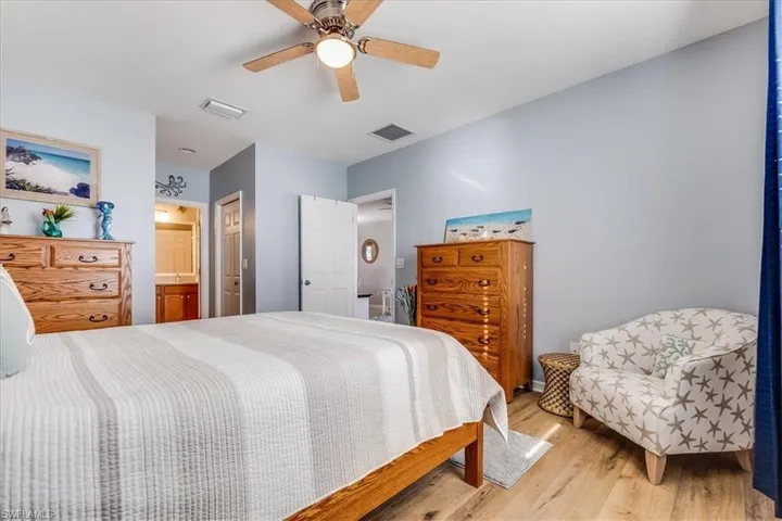 Bedroom with connected bathroom and 2 walk in closets. Features ceiling fan and light laminate flooring