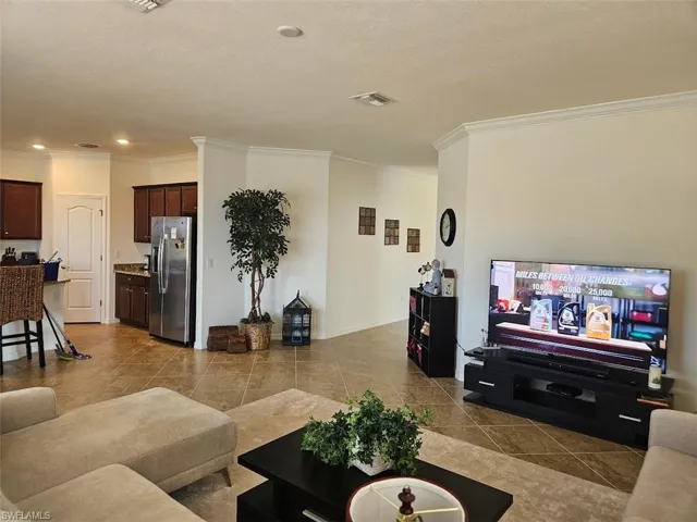 Living room with crown molding, a textured ceiling, and light tile patterned floors