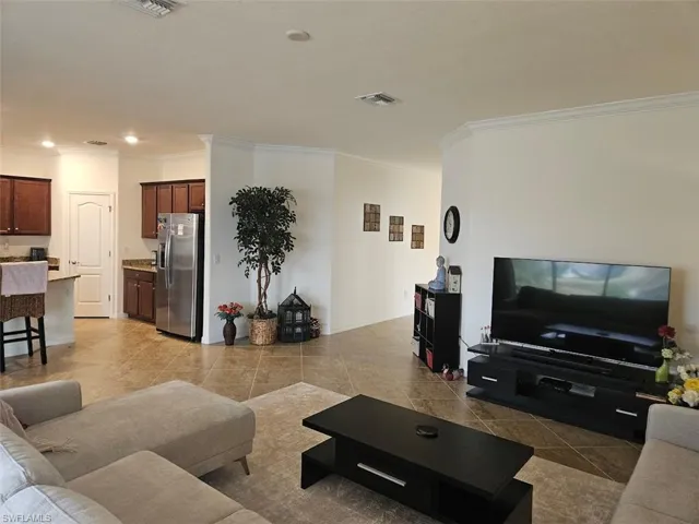 Living room with light tile patterned floors and ornamental molding