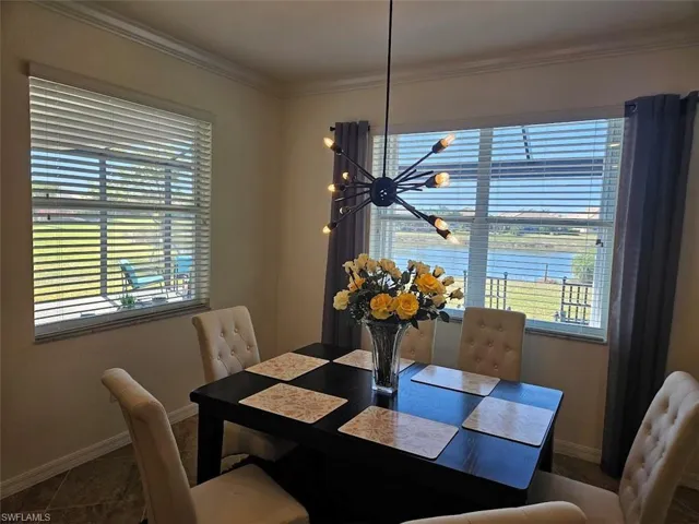 Dining area featuring a notable chandelier, crown molding, a healthy amount of sunlight, and a water view