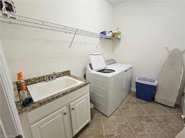 Laundry area with sink, independent washer and dryer, and light tile floors