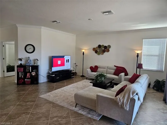 Tiled living room with crown molding and a textured ceiling