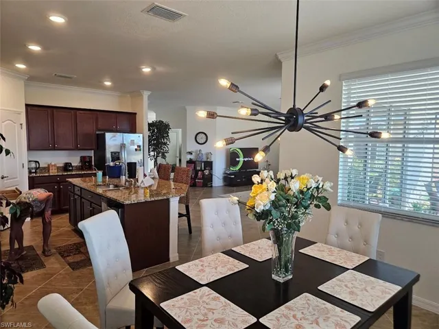Tiled dining space with crown molding, plenty of natural light, and sink