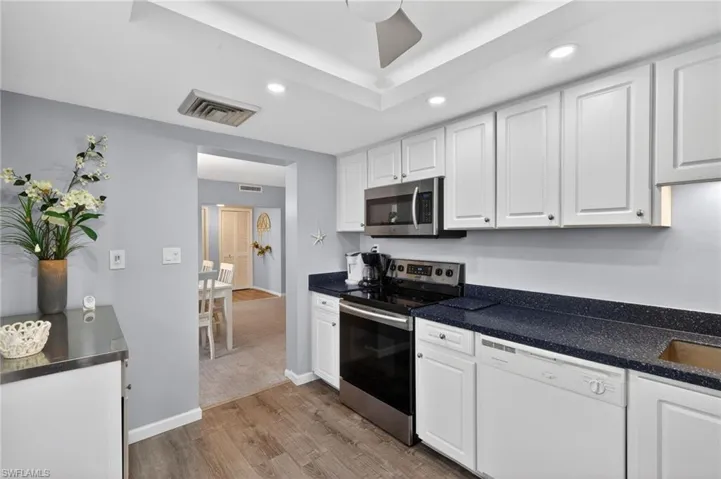 Kitchen featuring white cabinetry, stainless steel appliances, recessed lighting, light wood-type flooring. - Virtually Edited Image