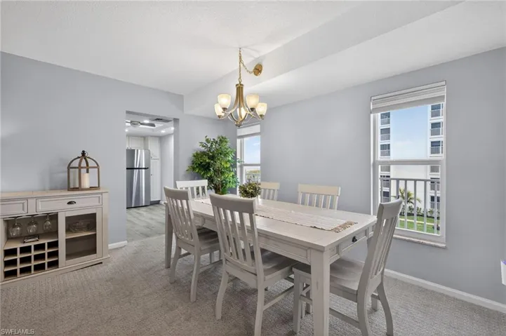 Dining area featuring light colored carpet and easy access to the kitchen. - Virtually Edited Image