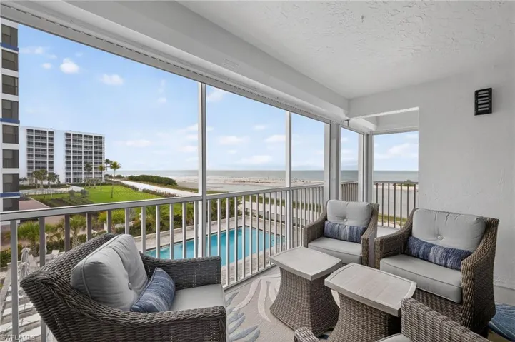 Lanai with views of the pool and Gulf of Mexico and electric shutters. Ample room for relaxing and enjoying the sunset. - Virtually Edited Image