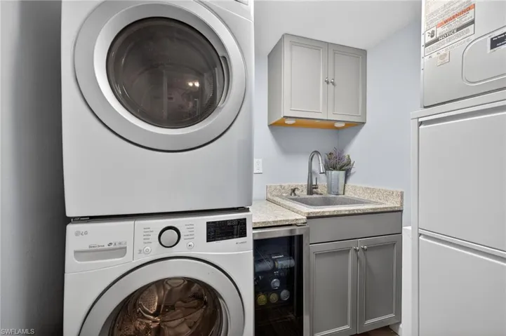 Laundry room featuring beverage cooler, stacked washer / drying machine, and extra storage space. - Virtually Edited Image