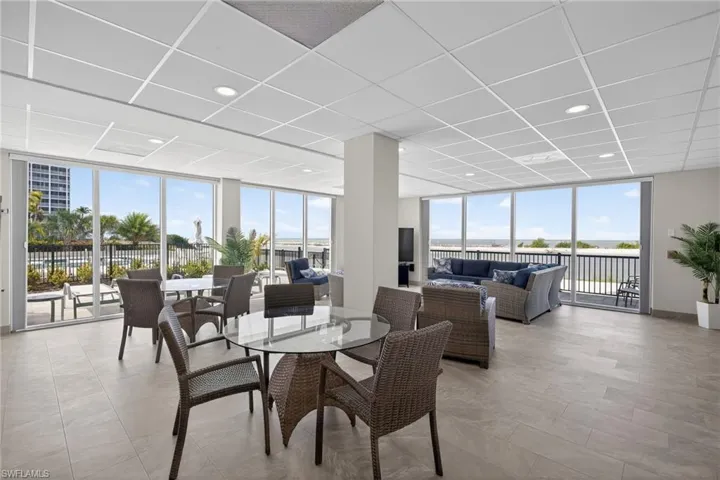 Community gathering room with expansive windows offering beautiful views of the Gulf of Mexico. - Virtually Edited Image