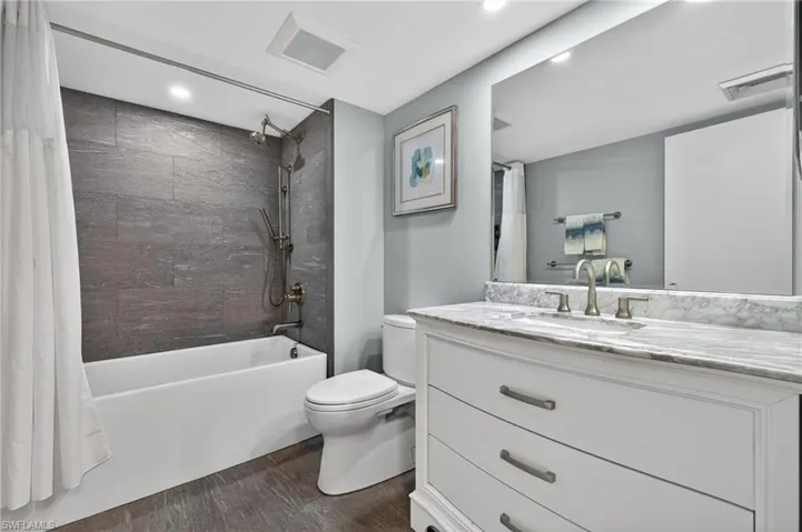 Full bath with large vanity, dark wood-type flooring, shower / bath combo, and recessed lighting. - Virtually Edited Image