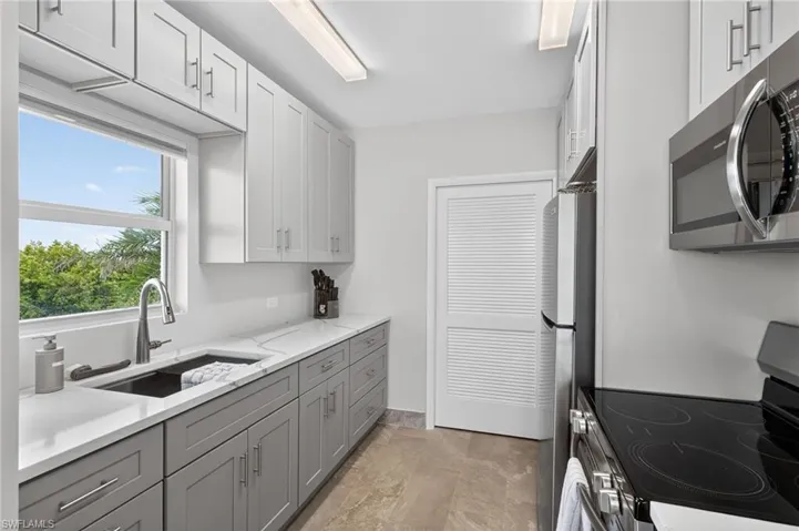 Community kitchen featuring stainless steel appliances, light stone countertops, and two tone color scheme. - Virtually Edited Image