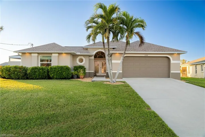 Single story home with a garage and a front lawn