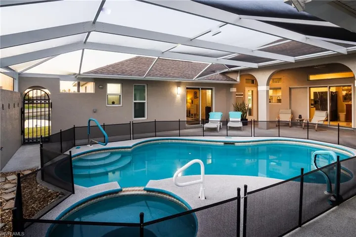 View of swimming pool featuring glass enclosure, an in ground hot tub, and a patio