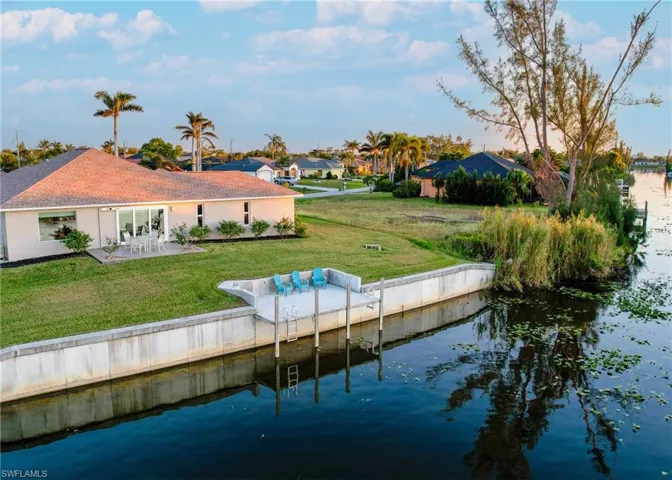 Back of house featuring a yard, a water view, and a patio area