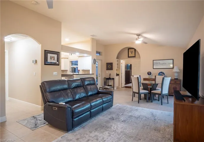 Tiled living room with ceiling fan and vaulted ceiling