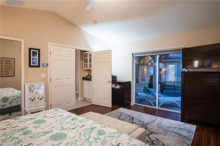 Bedroom with access to outside, vaulted ceiling, dark hardwood / wood-style floors, and ceiling fan
