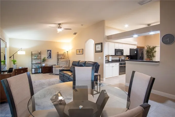Tiled dining area with ceiling fan and lofted ceiling