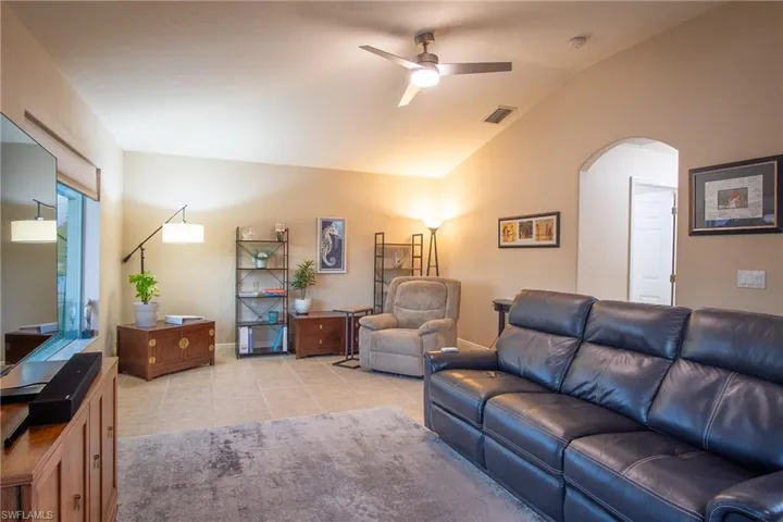 Living room featuring ceiling fan, light tile patterned floors, and lofted ceiling