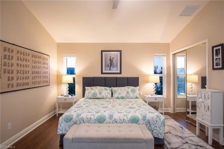 Bedroom with vaulted ceiling, ceiling fan, a closet, and dark hardwood / wood-style floors