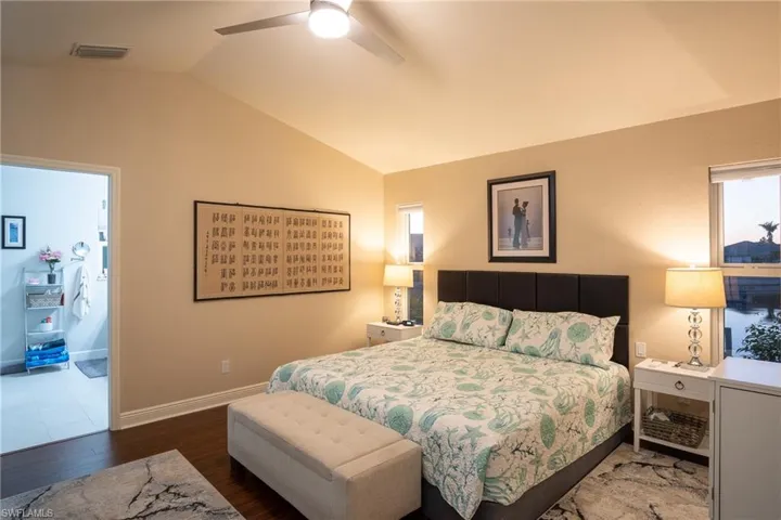 Bedroom with ceiling fan, dark wood-type flooring, and vaulted ceiling