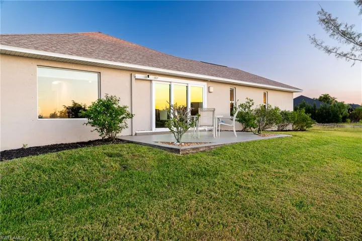 Back house at dusk featuring a patio area and a yard