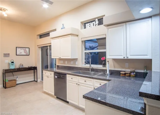 Kitchen featuring dishwasher, white cabinetry, and sink