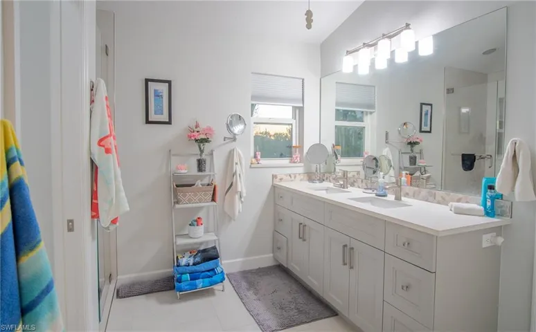 Bathroom featuring tile patterned floors, vanity, a shower with shower door, and vaulted ceiling