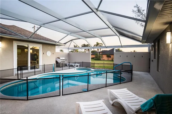 View of swimming pool featuring an in ground hot tub, a patio, glass enclosure, and a grill
