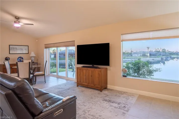 Living room featuring tile patterned floors, ceiling fan, and lofted ceiling