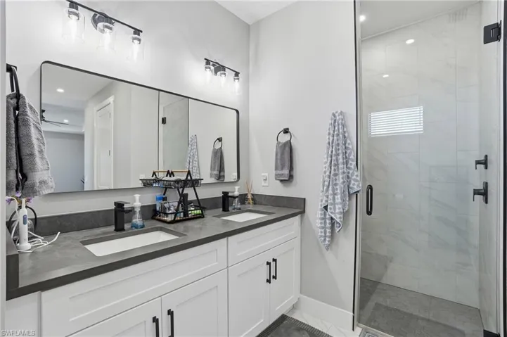 Bathroom with double vanity, a stall shower, and recessed lighting