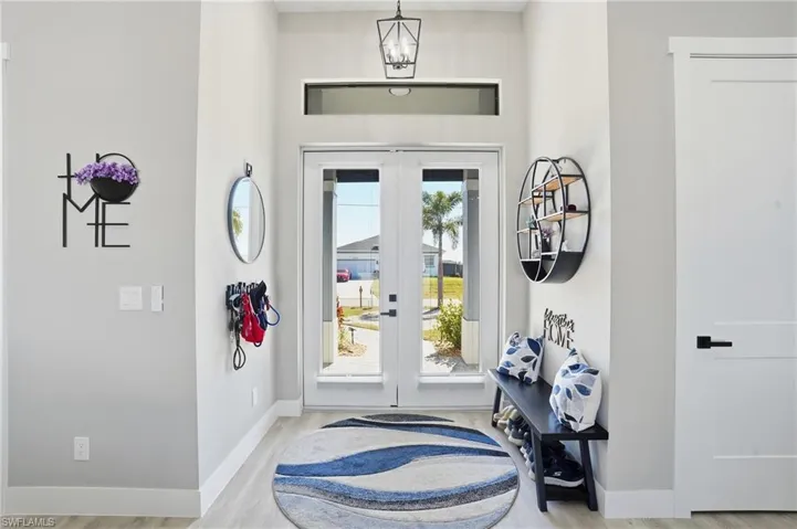 Entrance foyer featuring french doors, a chandelier, and light wood finished floors