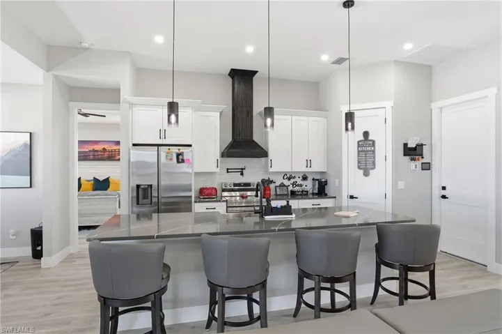 Kitchen with white cabinetry, stainless steel appliances, light wood-style floors, a kitchen breakfast bar, and tasteful backsplash