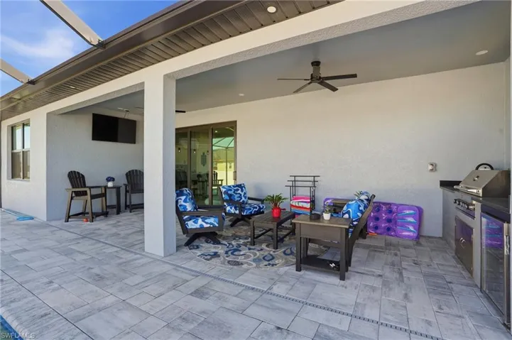 View of patio with ceiling fan, a grill, and glass enclosure