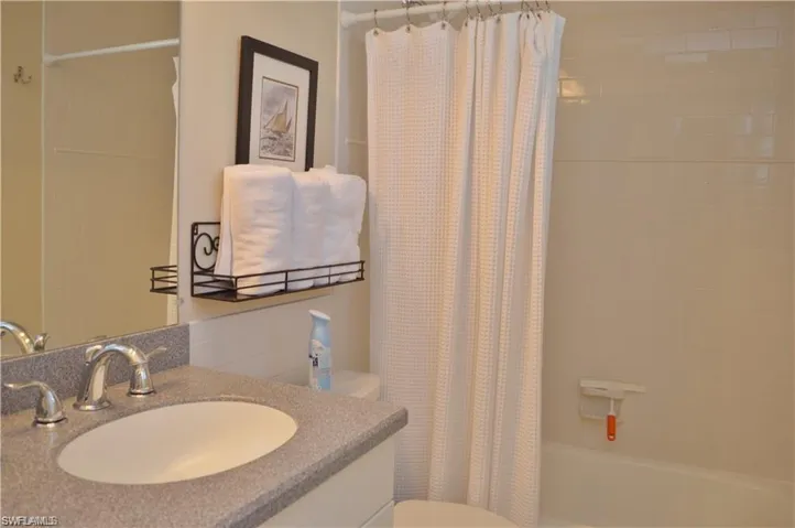 Full bathroom featuring toilet, shower / bath combination with curtain, and vanity