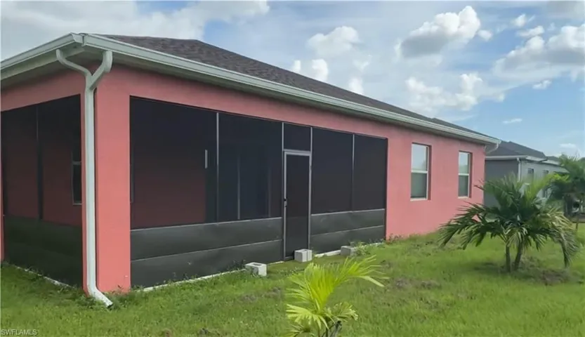 View of home's exterior with a sunroom, stucco siding, and a lawn