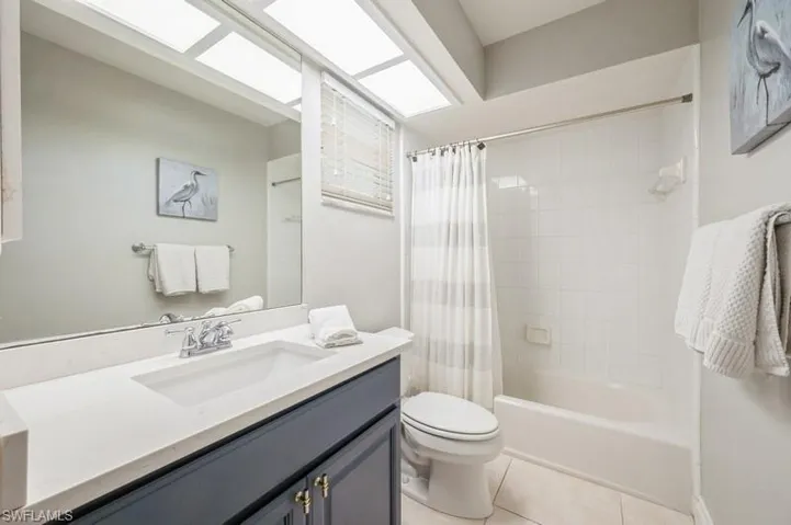 Full bathroom featuring tile patterned flooring, vanity, toilet, and shower / bathtub combination with curtain