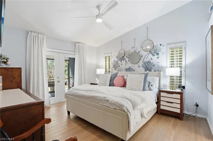 Bedroom featuring french doors, light wood-style floors, vaulted ceiling, access to outside, and multiple windows