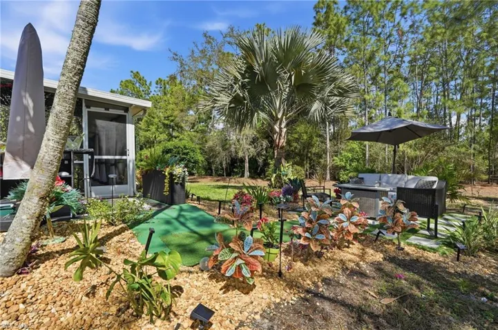 View of yard featuring an outdoor living space, view of wooded area, and a patio area